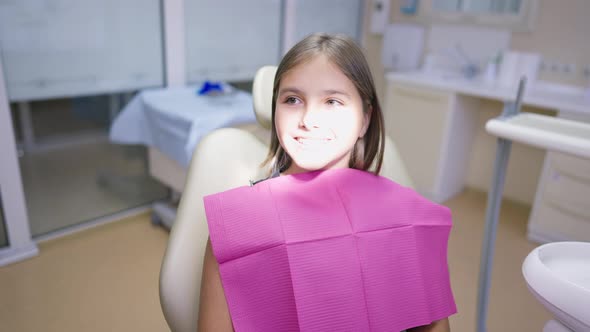 Cute Brunette Teenage Girl with Brown Eyes Smiling As Dental Light Shines on Face in Slow Motion