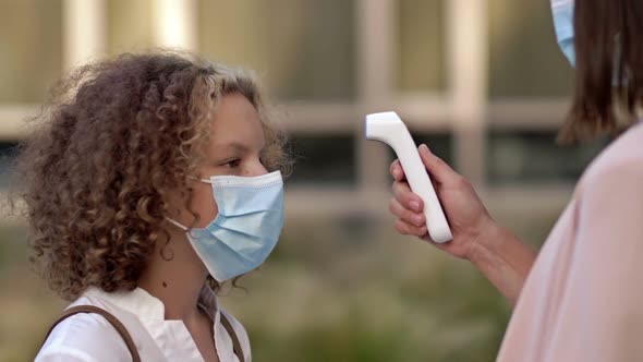 Teacher Woman Measures School Girl Temperature with Digital Thermometer