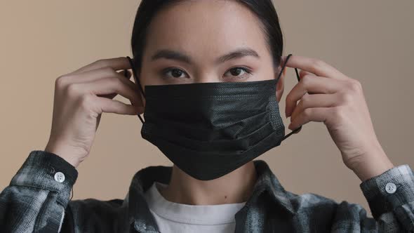 Portrait Serious Asian Girl Sick Woman Indoors Putting on Face Protective Black Medical Mask
