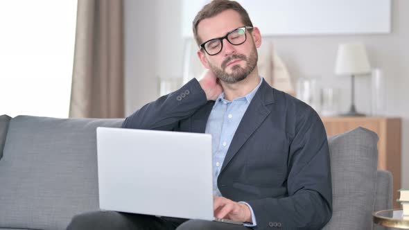 Young Businessman with Laptop Having Neck Pain at Home