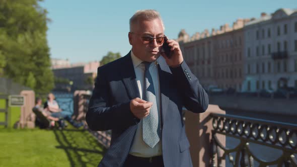 Concerned Senior Business Leader Arguing on Phone Outdoors.