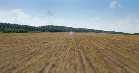 A Tractor Drives Fertilizer Across A Mown Field 