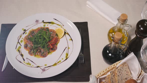 Beef o Fish Carpaccio with Parmesan Lemon and Arugula in Modern Restaurant Top View