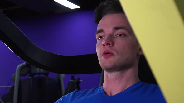 A Young Fit Man Trains on a Machine in a Gym - Face Closeup