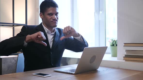 Thumbs Down by Black Businessman while Working on Laptop