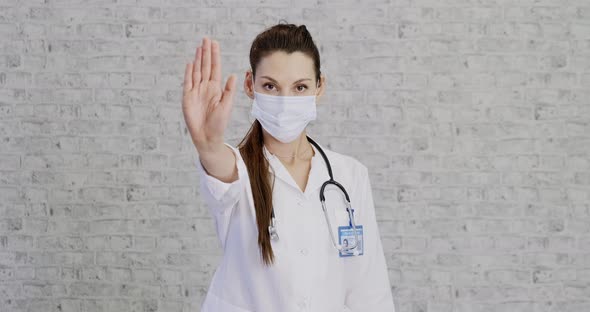 Doctor Woman Makes Stopping Hand Gesture. Girl Doctor Wearing Protection Face Mask Against Covid-19