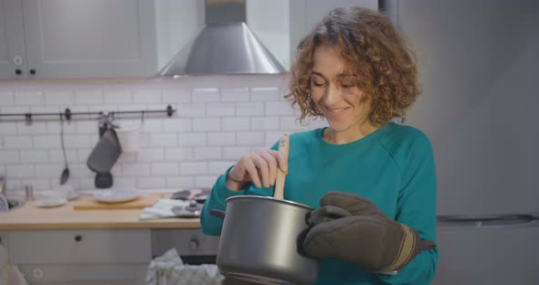 Pretty Young Woman Cooking in Pan in Modern Kitchen