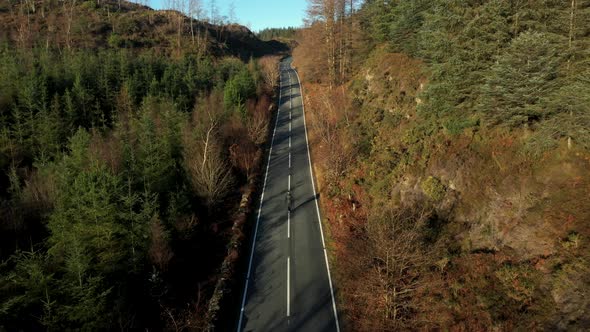 Aerial view of a woman walking on a countryside mountain road in Wales