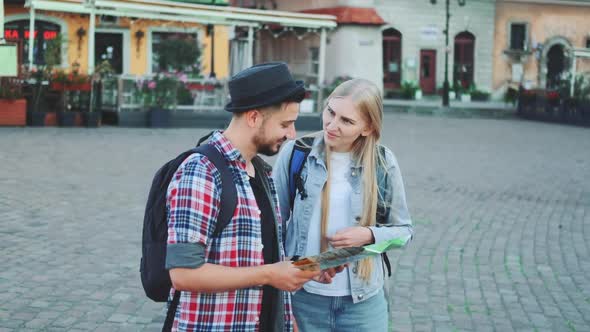 Young Tourists Couple Finding Necessary Destination on Map and Admiring Surroundings