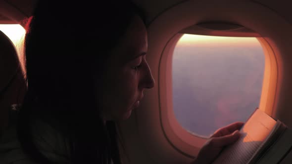 Woman Reading Book Inside Airplane