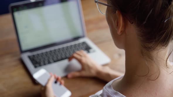 Adult woman in glasses working on laptop