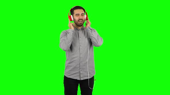 Brunette Guy Is Dancing and Enjoying Music in Big Red Headphones. Green Screen