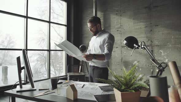 Creative Architect Thinking on Big Drawings Standing Faces To Window