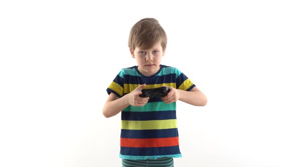 Little Boy in the Studio on a White Background Plays the Joystick in Video Games