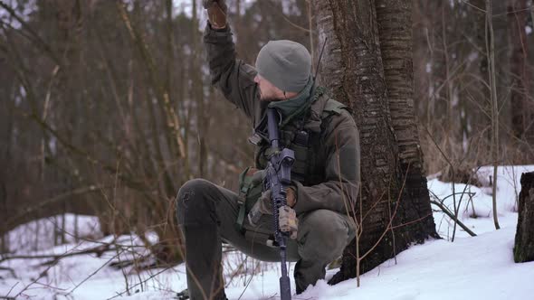 Portrait of Serious Young Handsome Soldier Gesturing As Man and Woman Approaching with Weapon