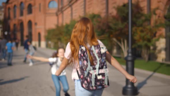 Happy Schoolgirls Meeting Outdoors and Embracing Happy To See Each Other