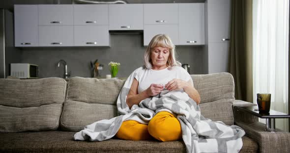 Aged Woman with Migraine Taking Pill on Sofa