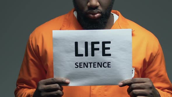 Life Sentence Phrase on Cardboard in Hands of Afro-American Dangerous Prisoner