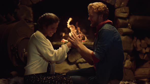 Loving Couple Warming Fireplace in Country House