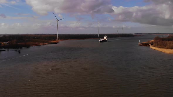 Aerial Over Oude Maas With Greetje Cargo Seen In Distance And Wind Turbines Alongside Riverbank