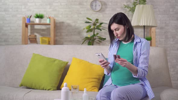 Puzzled Young Pregnant Woman with Pills in Her Hands Searches the Internet