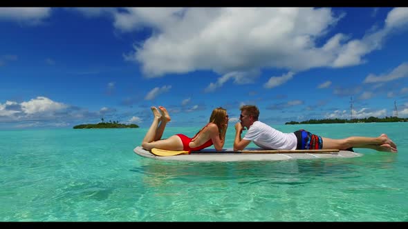 Two people relax on paradise island beach wildlife by blue lagoon and white sand background of the M