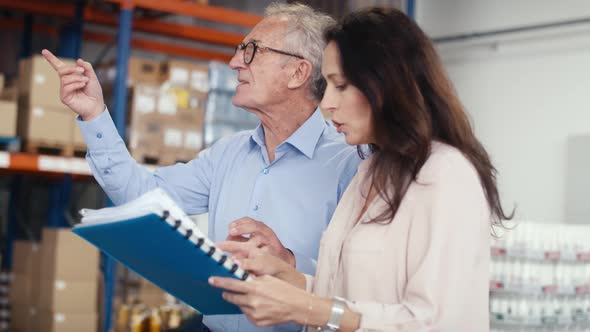 Mature woman and man analyzing documents in the warehouse. Shot with RED helium camera in 8K.