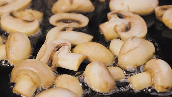 The Process of Cooking Fried Champignon Mushrooms in Olive Oil in a Frying Pan Close Up