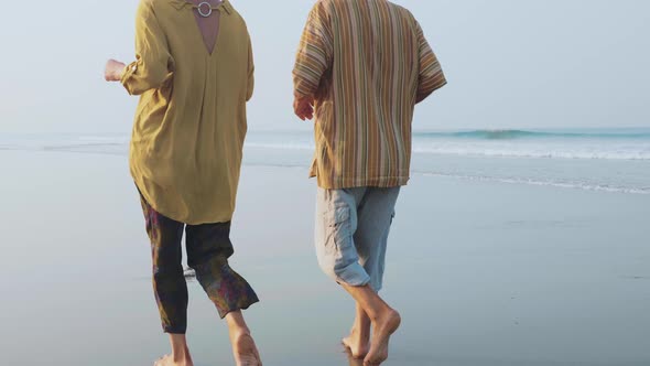 Active Senior Couple Running on the Sandy Beach at Sunrise