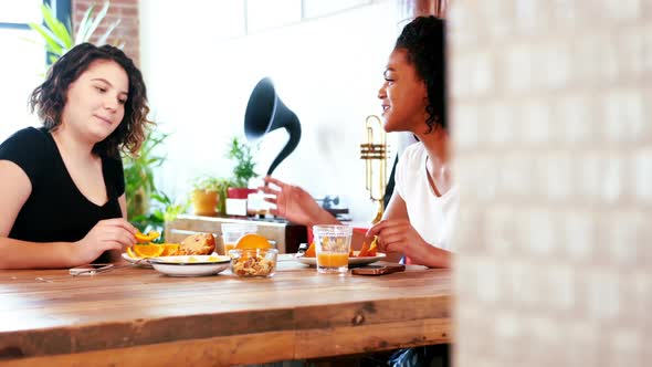 Lesbian couple interacting with each other while having breakfast