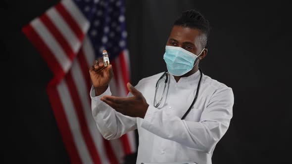 African American Male Scientist in Coronavirus Face Mask Presenting Covid19 Vaccine at Press