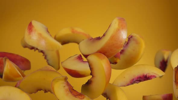 Closeup of the Peach Slices Bouncing on the Yellow Background