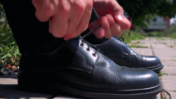Old Senior Man Ties Up Leather Shoes in the Park - Detail
