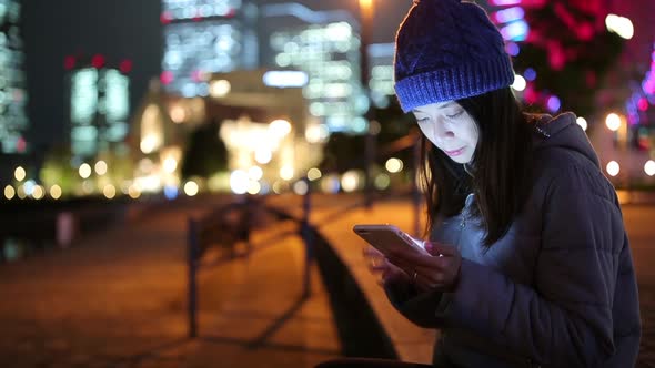 Woman using mobile phone in Yokohama city at night