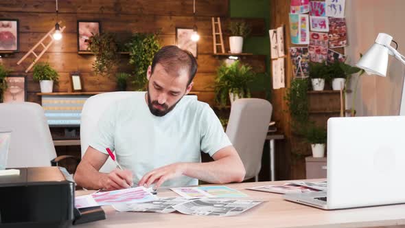 Creative Man Art Director Writing Down Notes While Looking at His Designs