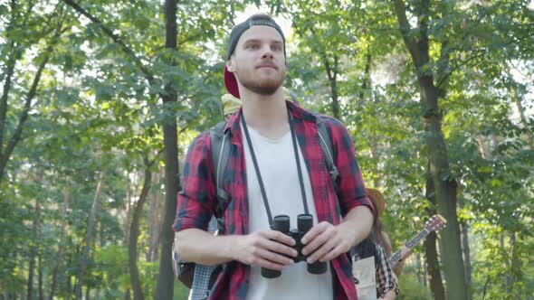 Confident Male Guide in Summer Forest with Group of Positive Young Tourists Strolling at the