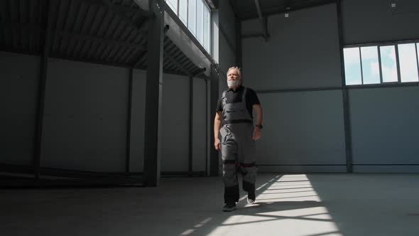 Slow Motion an Adult Grayhaired Man Worker Walks Through the Warehouse a Working Engineer Walks