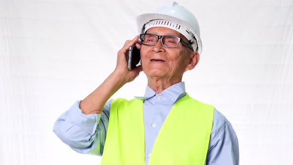 Senior engineering architect builder wearing safety vest and helmet discussing work on phone on