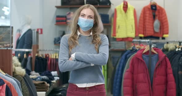 Beautiful Young Woman in Covid-19 Face Mask Crossing Hands and Looking at Camera. Portrait of