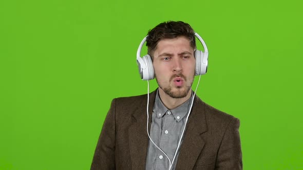 Man Listens To Music Through Headphones, Dances and Builds Grimaces. Green Screen. Slow Motion