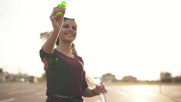 Young Hipster Girl with Long Braids Blowing Bubbles