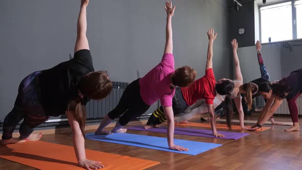 Young Woman Yoga Instructor Supervises the Performance of the Asana in a Group Lesson