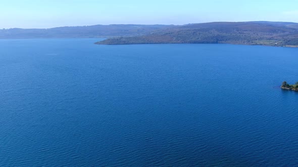 aerial view from drone over the lake with forests on the sides, its beach and garden area, small sai