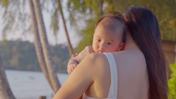 A young Asian mother is on the beach with her baby in summer time