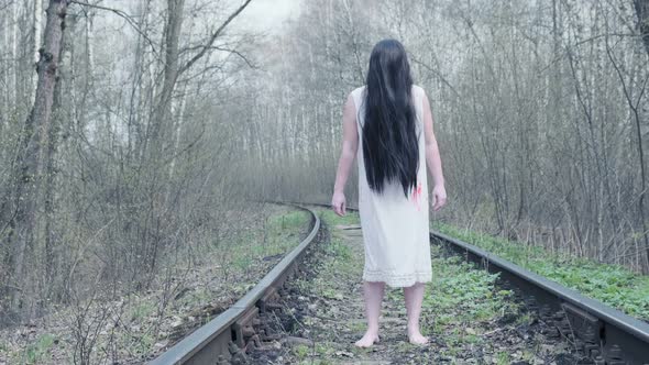 ghost of woman stands in forest on railway track