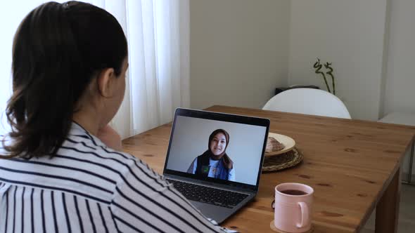 Women waving to each other in conversation with online camera.