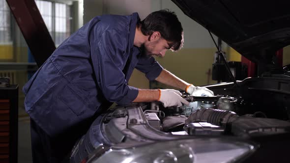 Auto Mechanic Using Flashlight To Look Under Hood