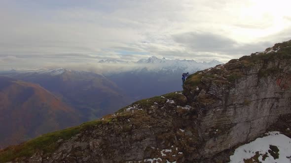 Aerial view of a trail runner running up the ridge of a snowy mountain