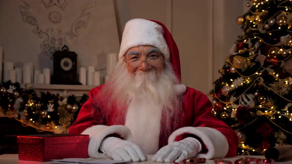 Smiling Santa Claus Looks Camera Sitting on Chair at Home