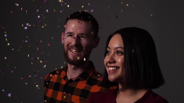 Two friends happily throw colorful confetti into the air which then slowly rains down on them - Slow